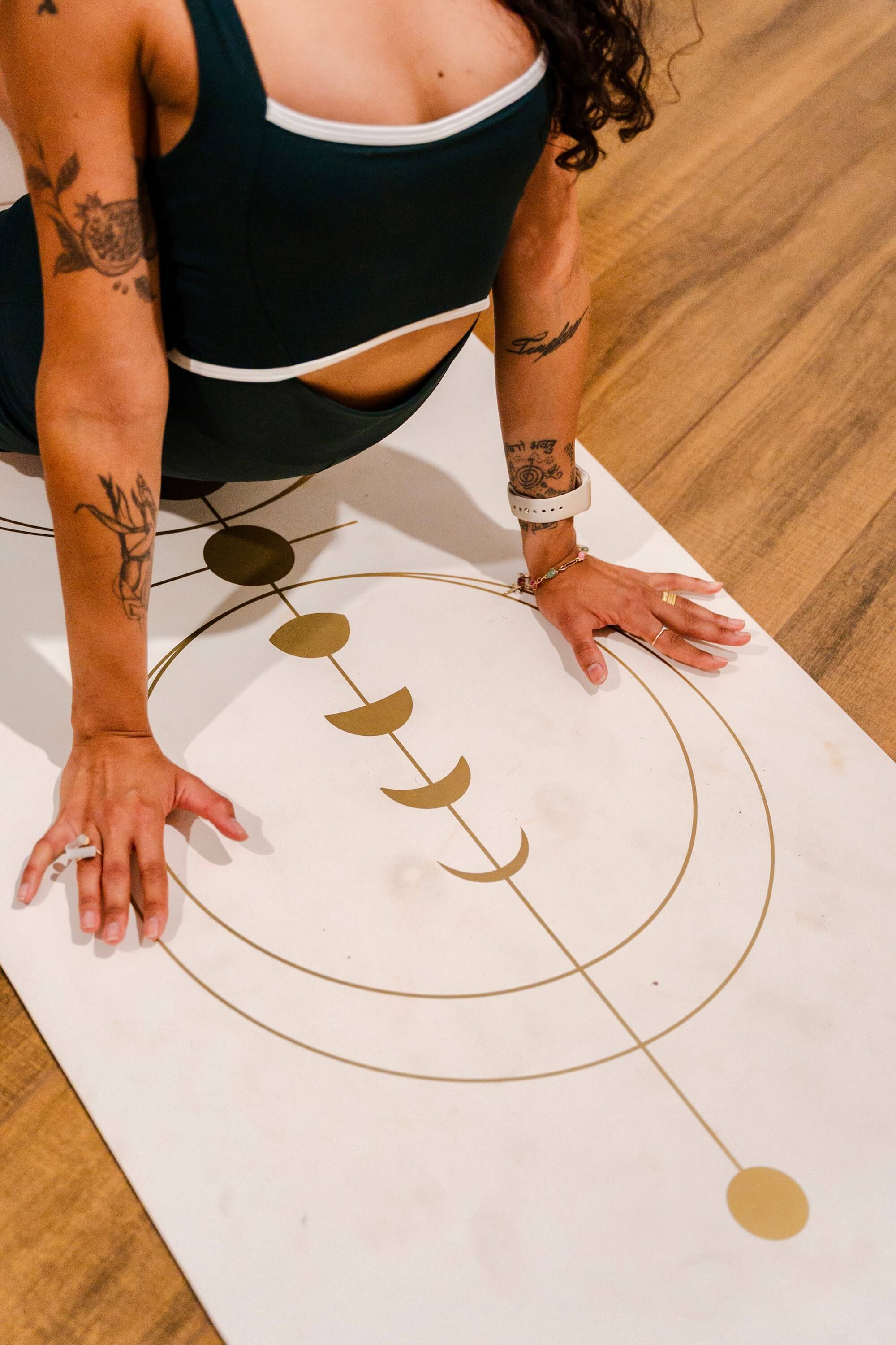 Person on a yoga mat with a gold design, wearing a black tank top